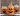 Different shaped glass jars with black jack-o-lantern face decals and orange jelly beans inside.